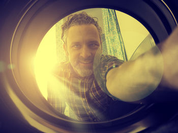 Close-up portrait of man seen through washing machine