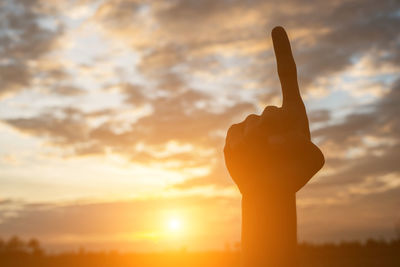 Close-up of silhouette hand against sky during sunset