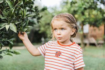 Close-up of cute girl standing by plant outdoors