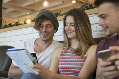 Three friends with notepad and cell phones in a cafe