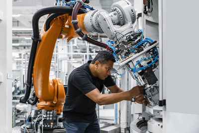 Engineer examining robotic arm in factory