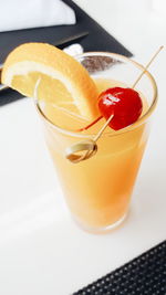 High angle view of fresh orange juice with cherry on skewer