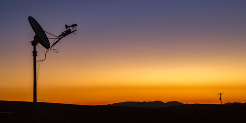 Silhouette street light against orange sky