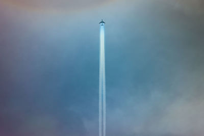 Low angle view of airplane against cloudy sky