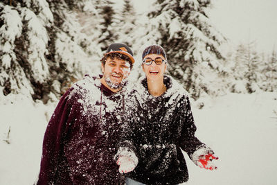 Cheerful couple playing with snow during winter