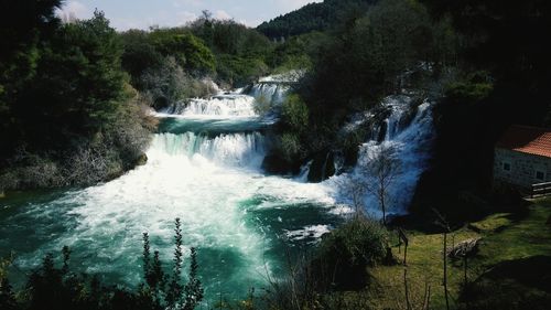 Scenic view of waterfall in forest against sky