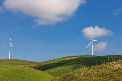 Windmills on field against sky