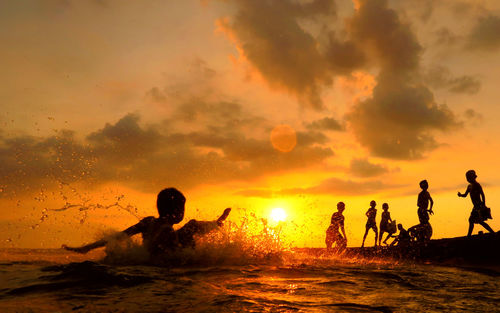 Kids playing in water at sunset