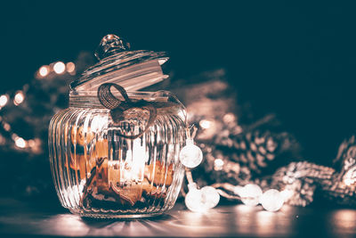 Illuminated glass jar with sweet food on table in christmas