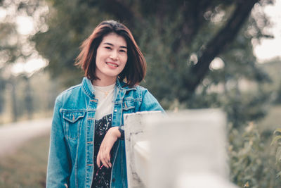 Portrait of young woman standing by railing