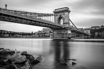 Low angle view of chain bridge over danube river against cloudy sky