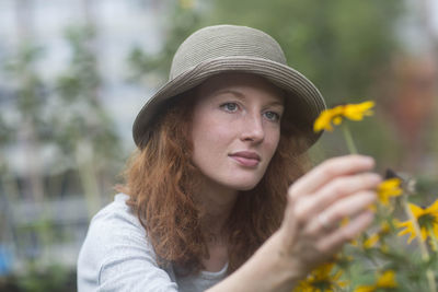 Young woman with hat outside holding bloom in the hand