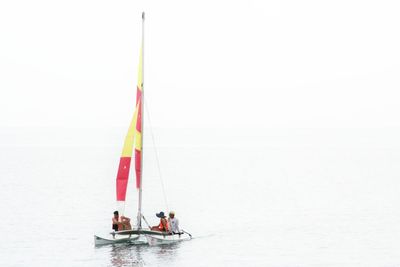 People on boat sailing in sea against clear sky