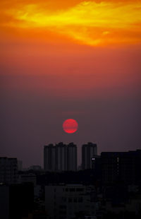 Silhouette buildings against dramatic sky during sunset