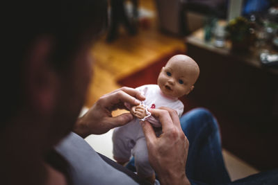 Close-up of man playing with doll at home