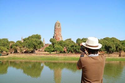 Man taking photos of the medieval prang of wat phra ram temple ruins in ayutthaya, thailand