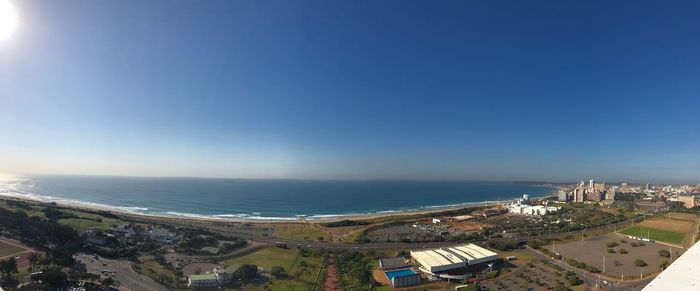 High angle view of buildings and sea against blue sky