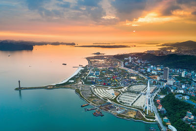 Aerial view of city by bay during sunset