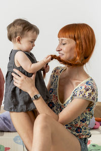 Redheaded mother having some fun and playing her baby girl daugh