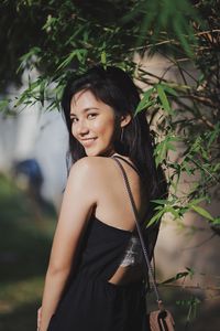 Portrait of young woman standing by plants