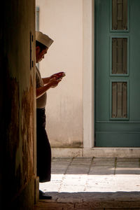 Side view of man standing against door