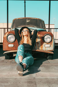 Portrait of young woman sitting on car