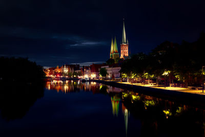 St mary church amidst illuminated houses by river at night