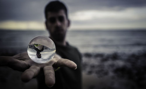 Man holding crystal ball at beach