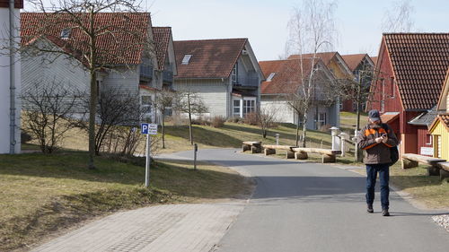 Man walking on road against buildings