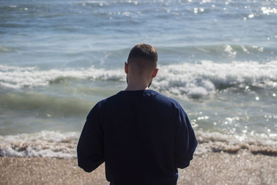 Rear view of man standing at beach