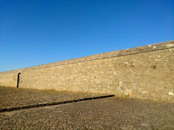 Low angle view of wall against clear blue sky