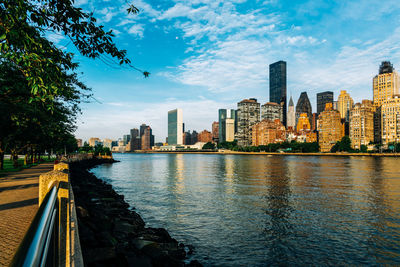 City at waterfront against cloudy sky