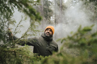 Male hiker exploring amidst plants in forest during vacation