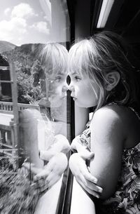 Side view of girl reflecting on window in train