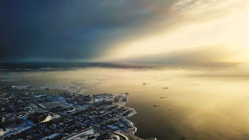 Aerial view of buildings and sea against sky during sunset