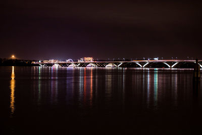 Illuminated bridge over river against sky at night