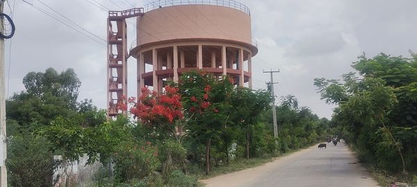 Road amidst trees in city against sky