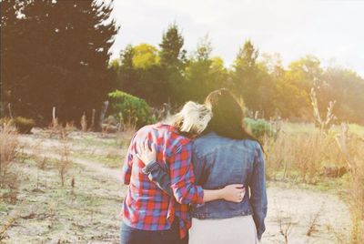 Rear view of two women with arm around each other in field