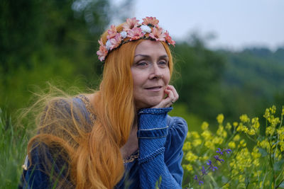 Portrait of beautiful woman with red flowers in field