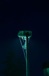 Low angle view of illuminated pole against blue sky at night