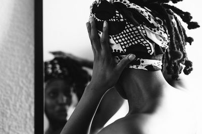 Woman wearing bandana reflecting on mirror at home