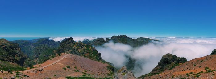 Scenic view of clouds covering mountains against blue sky