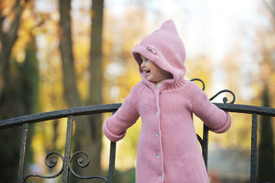 Cute girl looking away while standing against railing