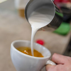 Close-up of hand pouring coffee cup