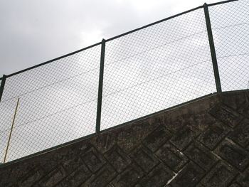Low angle view of chainlink fence against sky