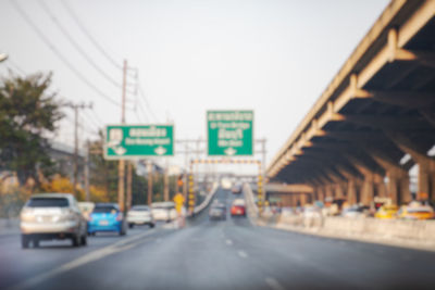 Vehicles on road against sky in city