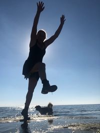Low angle view of man jumping at beach against sky