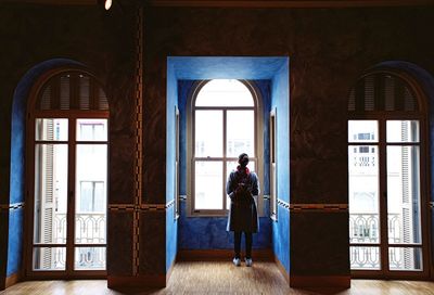 Rear view of woman standing against window