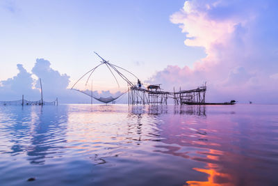 Fishing nets over sea against sky during sunset