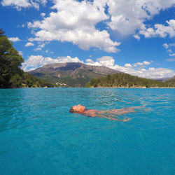 Woman swimming in turquoise sea against mountains